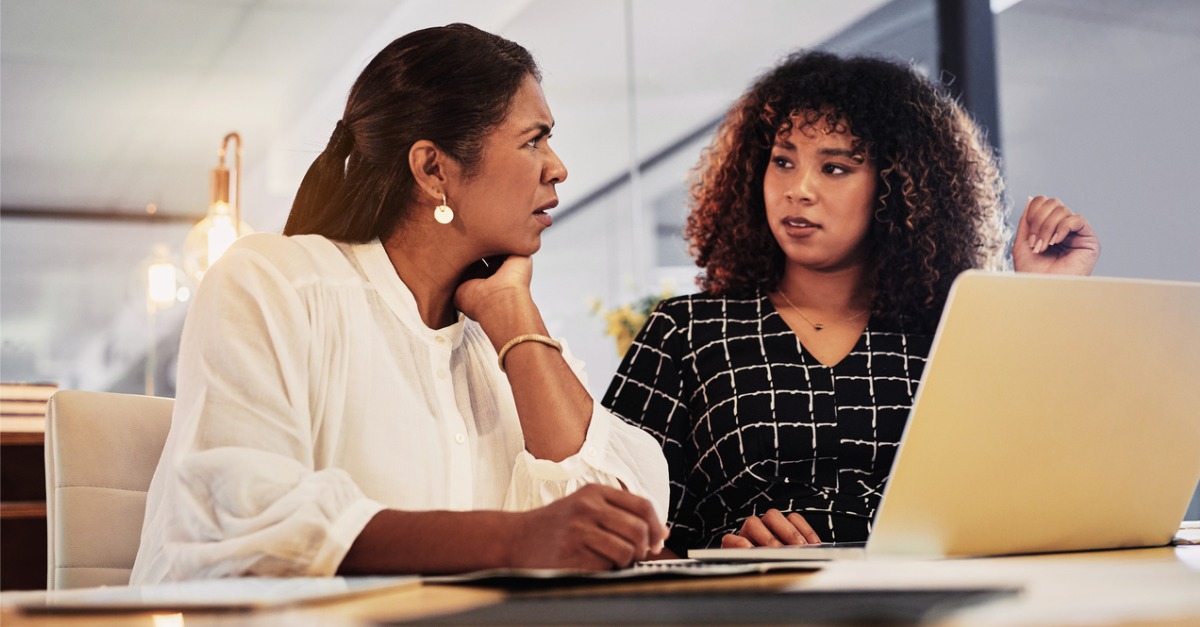 Photo showing two women using a laptop and discussing contact center automation tools.