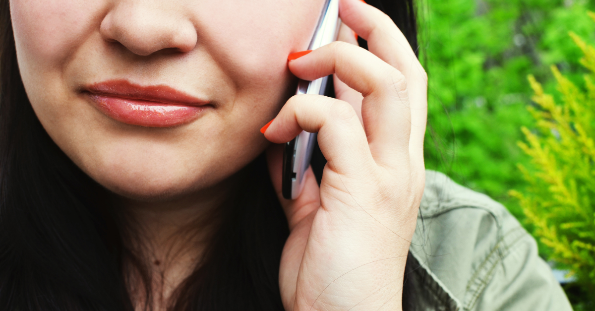 Close up photo of a woman talking to a smartphone, representing customer feedback, VoC strategies, and customer voice - important elements of conversational CX.